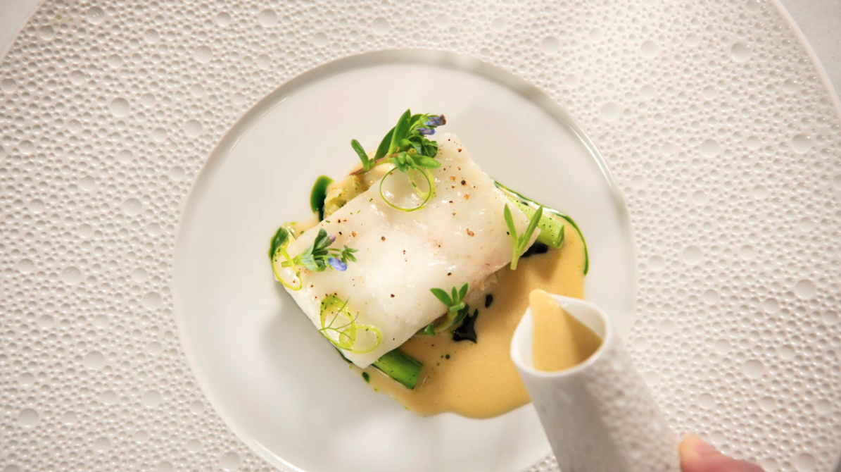 white plate with seafood dish and cream sauce poured on top